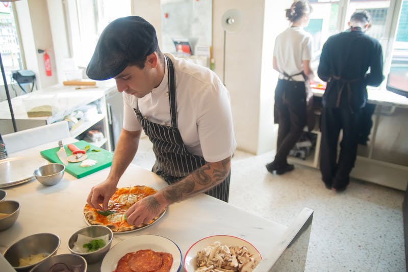 Staff preparing fresh pizza at Pizzana